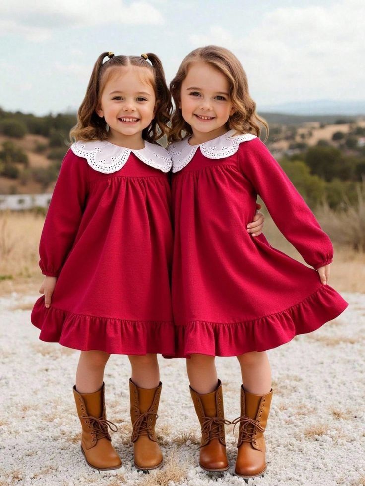 Two matching red holiday dresses with white collars and brown boots photographed in an outdoor setting.