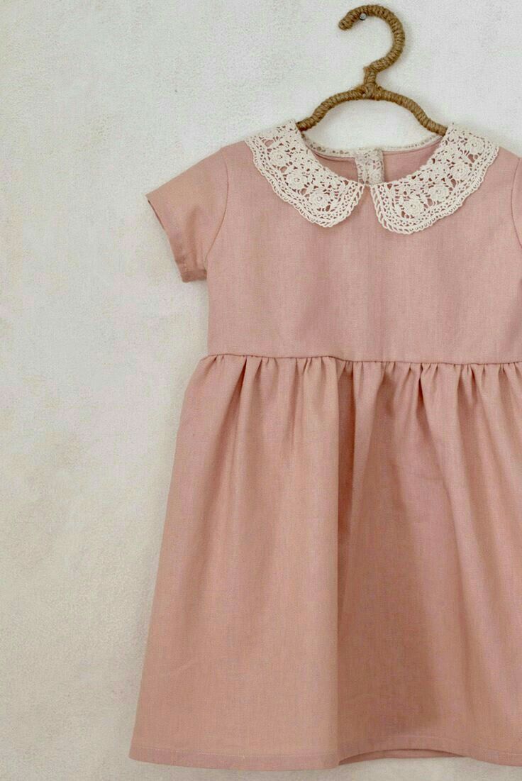 Pink linen girls dress with lace Peter Pan collar and short sleeves displayed on a hanger.