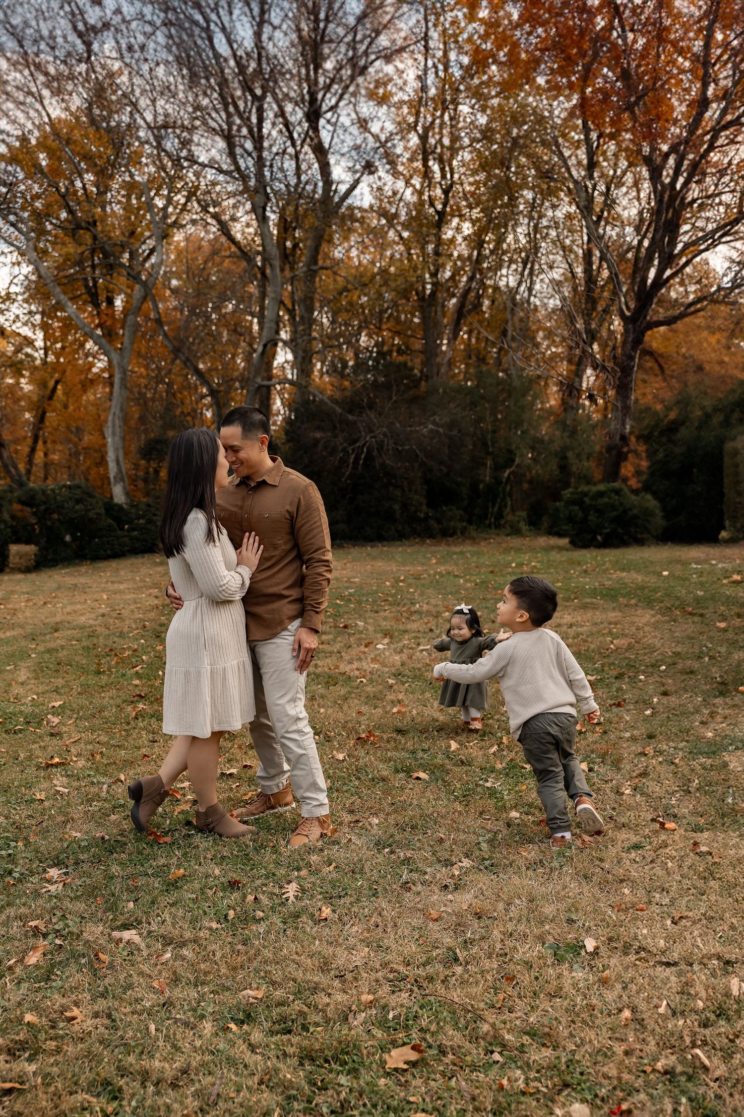 A family plays together in a golden autumn field during sunset, wearing casual clothing and sharing joyful moments.
