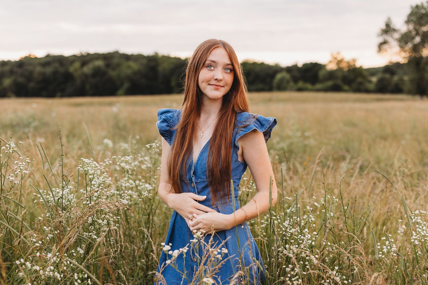 senior girl blue jean dress red hair field of wild grass and wild flowers