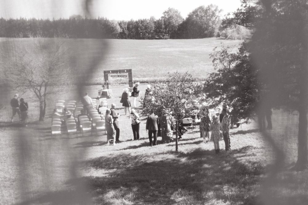 Vintage black and white photograph of people gathered outdoors at a rustic celebration.