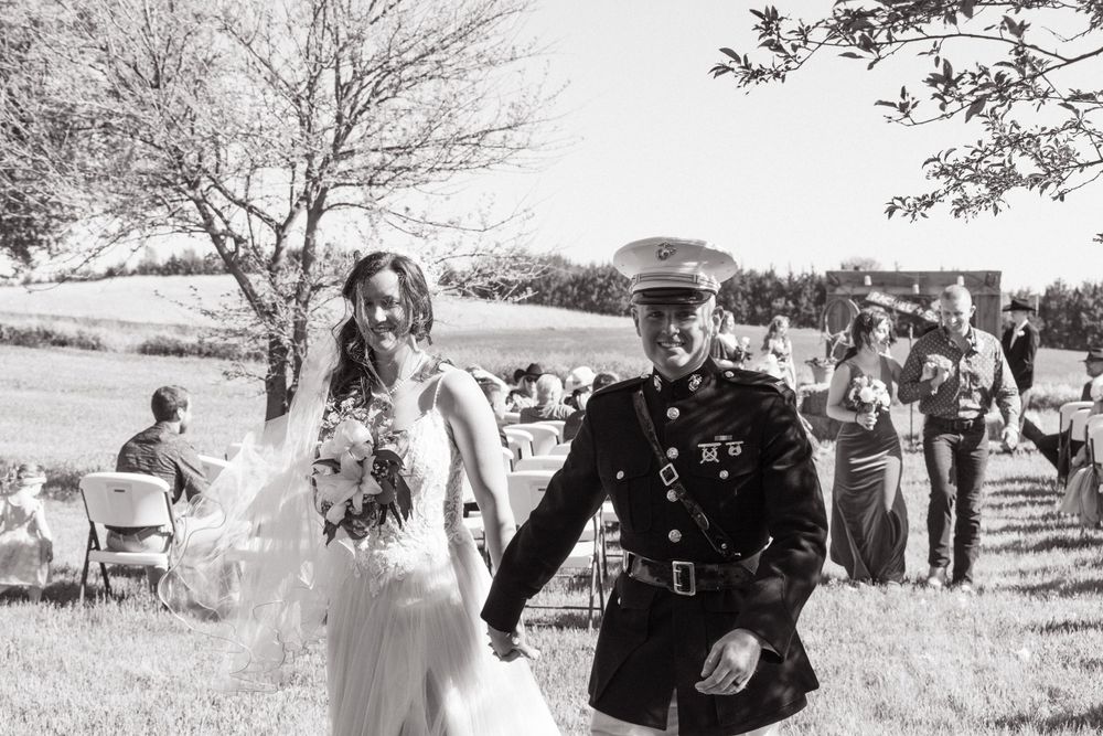 Military wedding ceremony taking place on a sunny day in an outdoor setting.