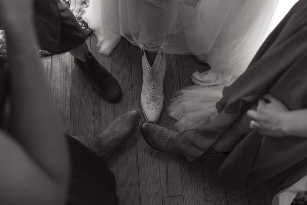 Close-up shot of formal shoes and dress hems on a wooden floor.