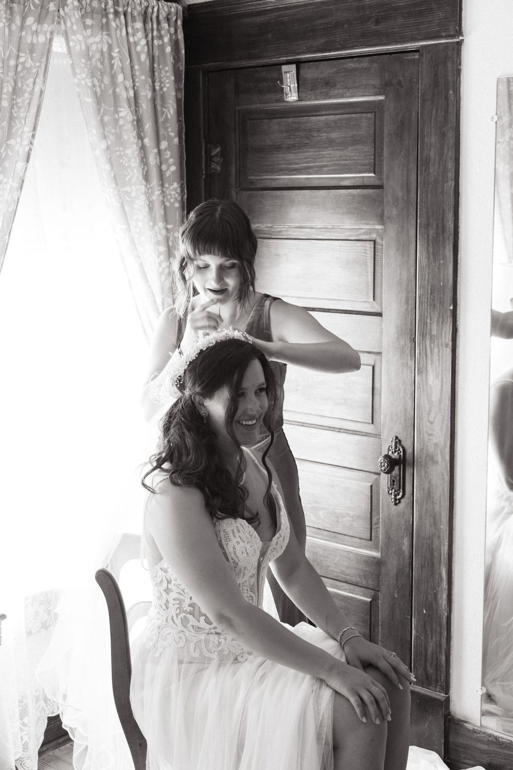 Black and white photo showing wedding preparation with styling in front of a wooden door.