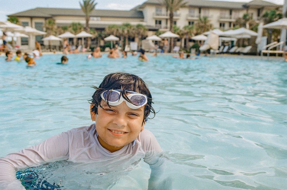 Swimming pool scene with person wearing goggles enjoying the water at a resort.
