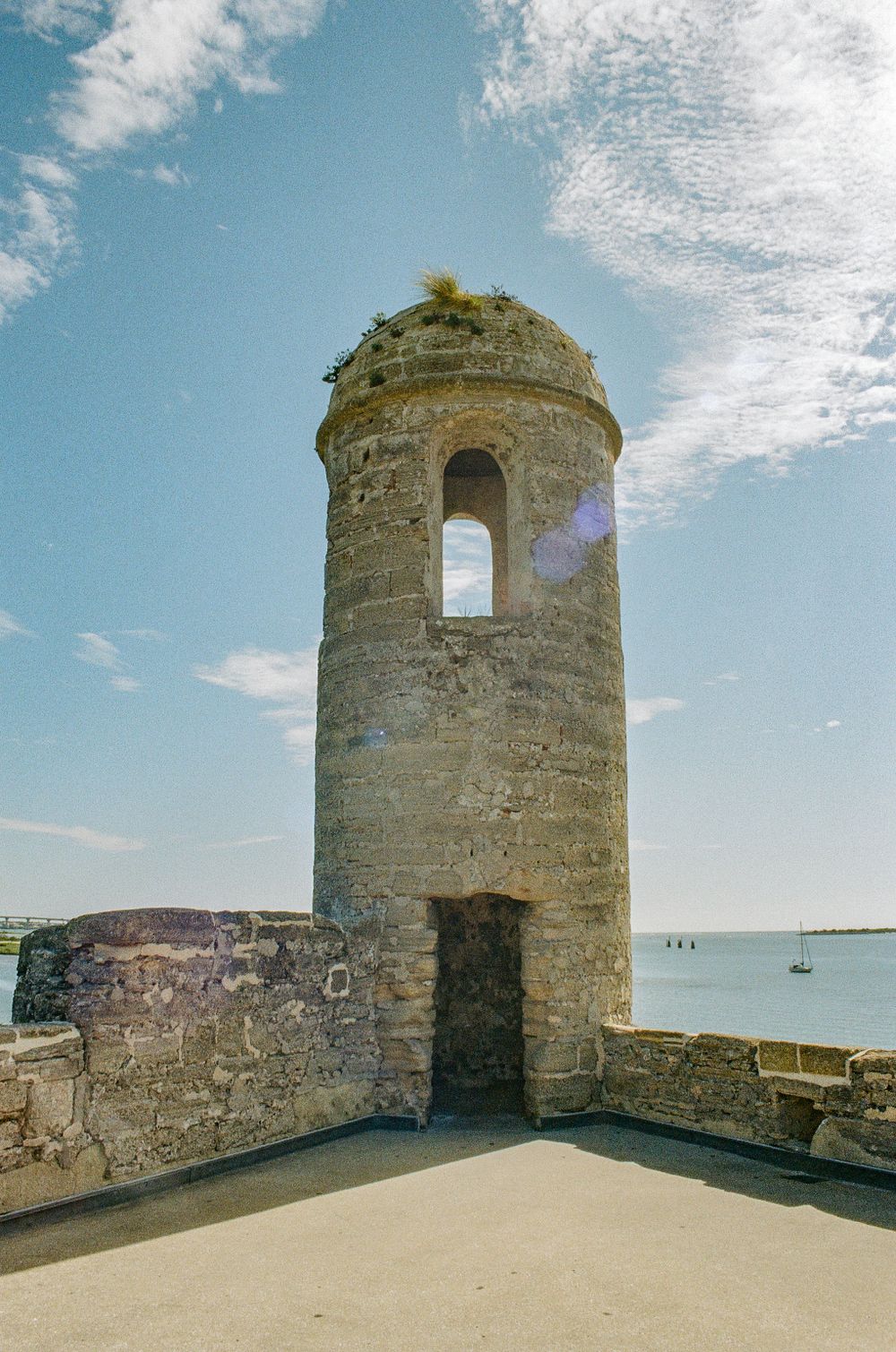 Ancient stone watchtower overlooking the sea with boats visible in the distance.