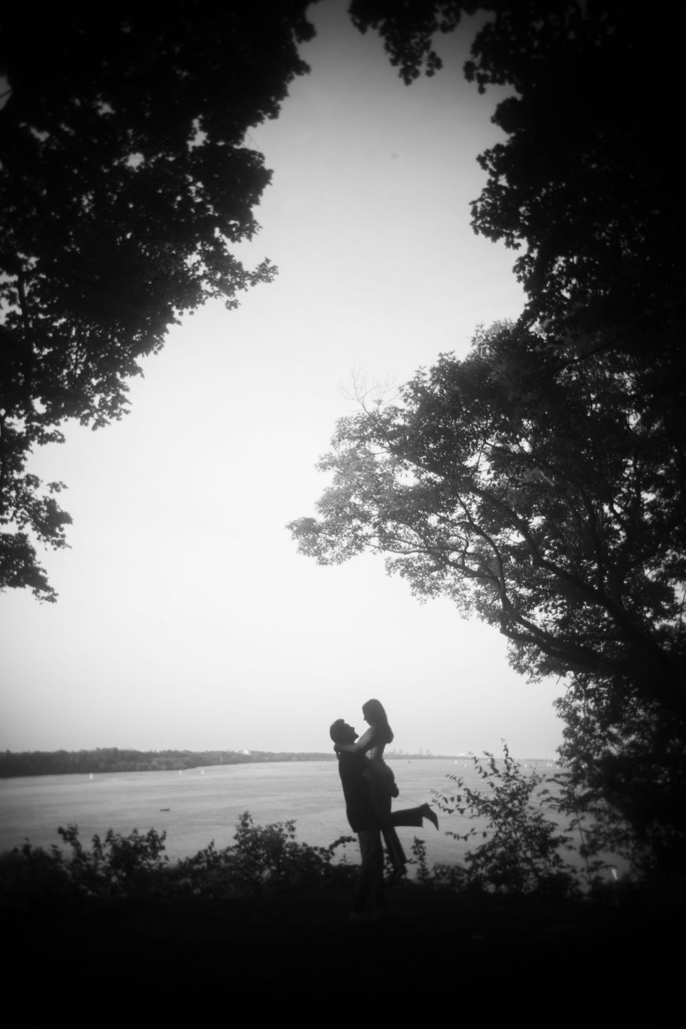 Silhouettes of figures against a serene sunset sky with trees framing the peaceful outdoor scene.