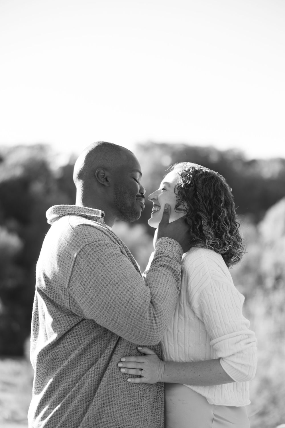 Black and white photo series showing a couple embracing outdoors in a romantic candid moment.