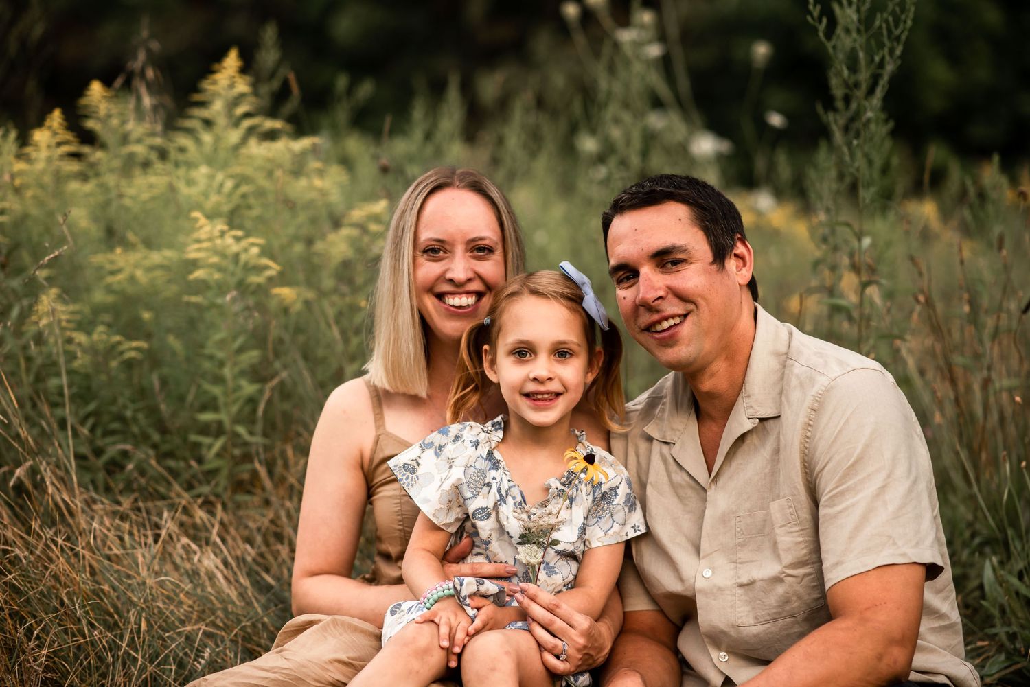 A family portrait session in a sun-drenched meadow with tall grasses and natural light.
