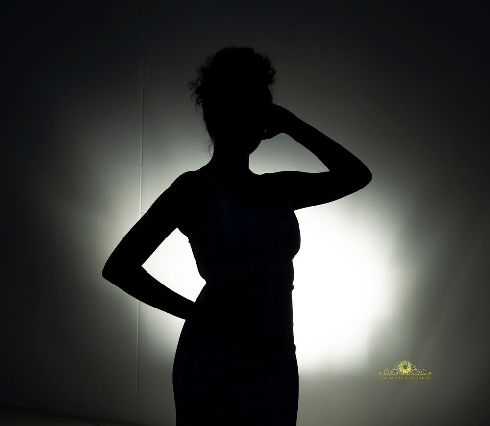 Dramatic silhouette portrait against bright backlight showing a striking pose.