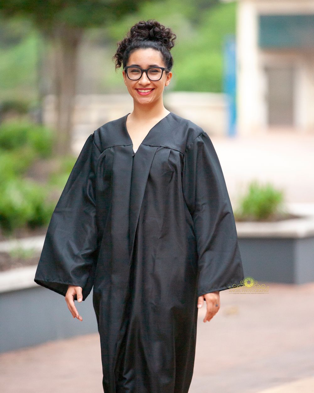 A graduate wearing traditional black commencement regalia outdoors.