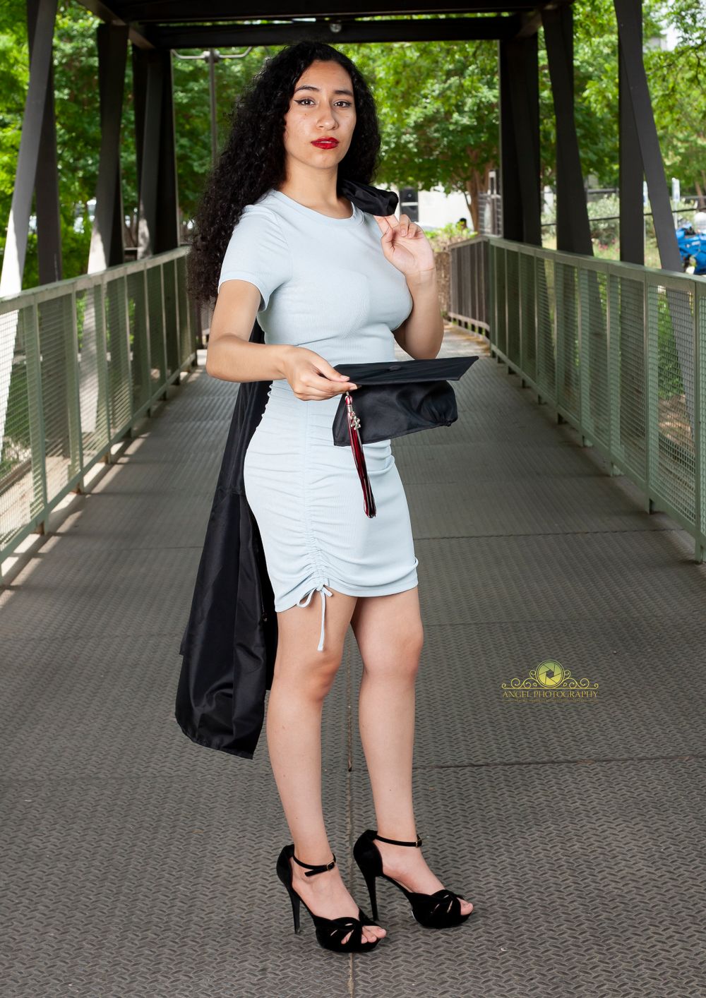 Stylish pose on wooden bridge walkway in fitted white dress and heels.