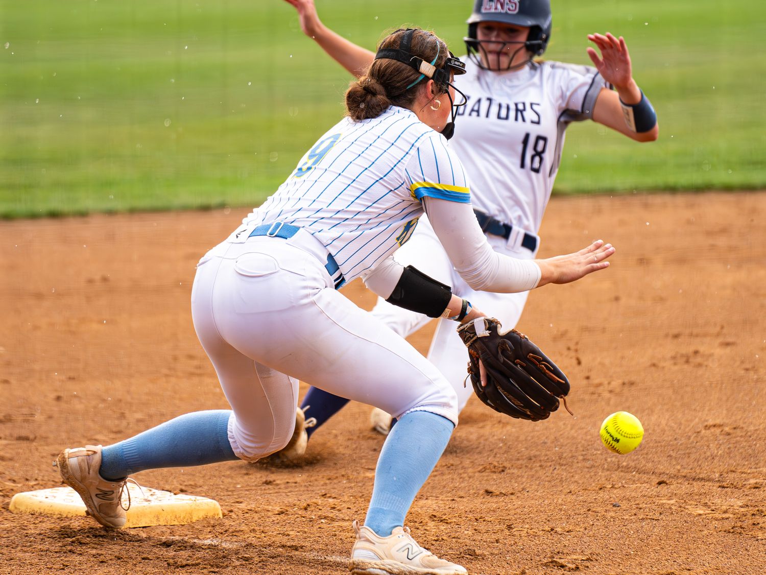 Softball players in action during an intense fielding play.