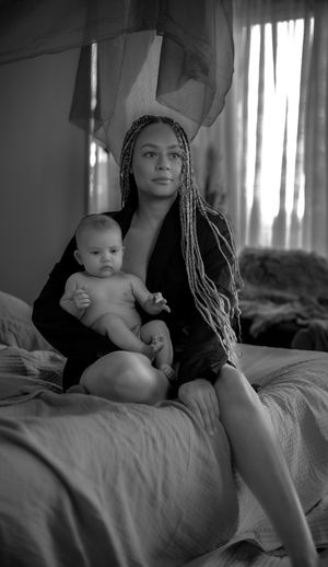 Mamma håller sitt barn stolt i en mysig studio.