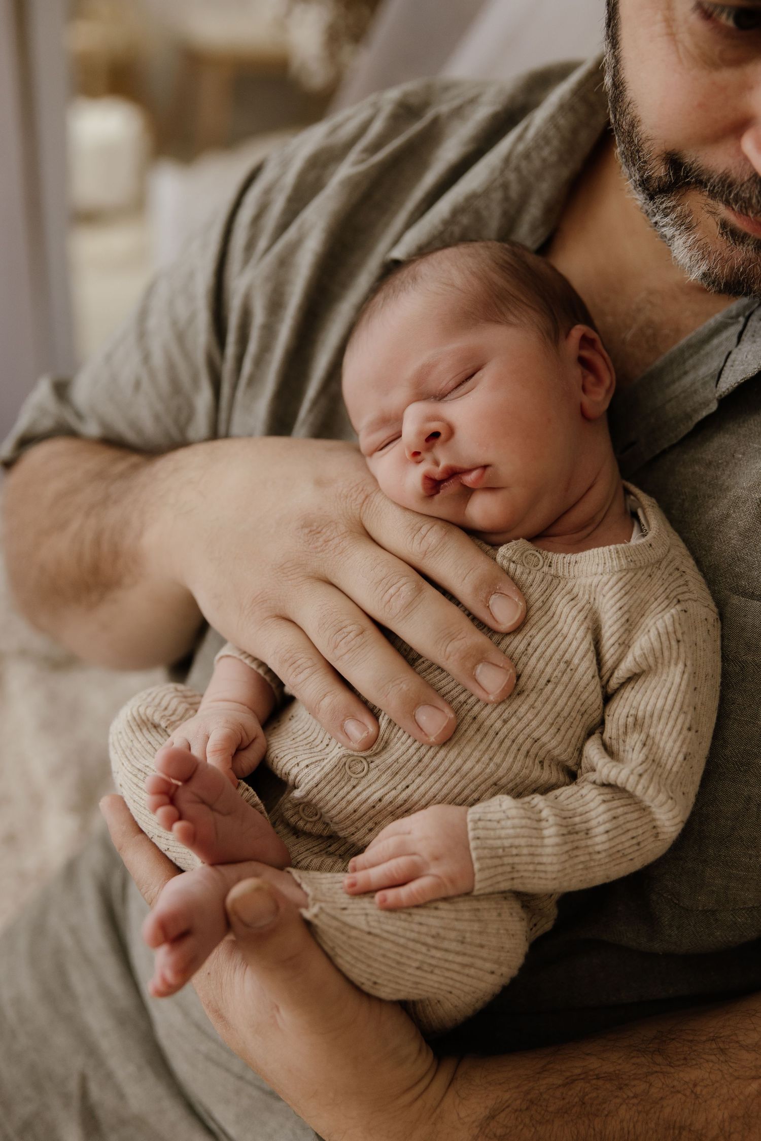 Close-up of baby sleeping peacefully in knit sweater while being held.
