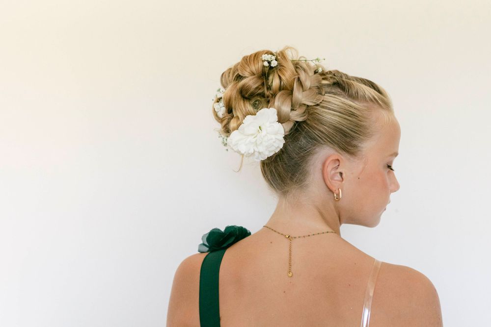 Elegant bridal updo hairstyle decorated with a white floral accessory.