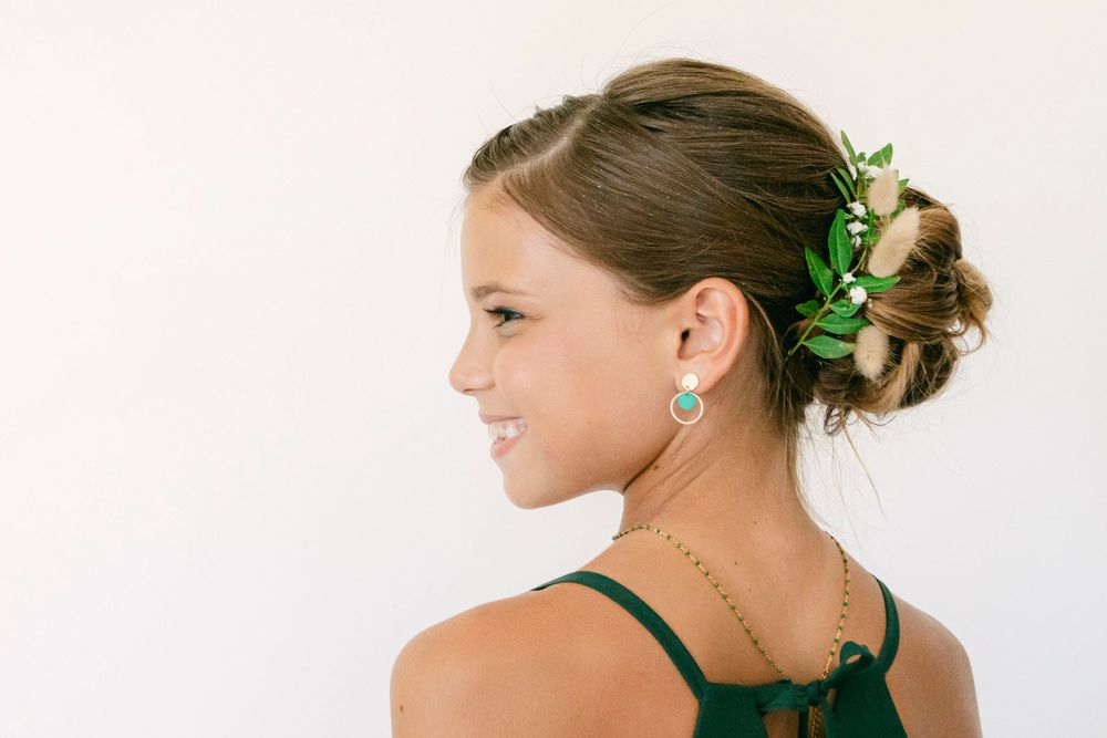 Side profile of an elegant updo hairstyle adorned with green leaves.