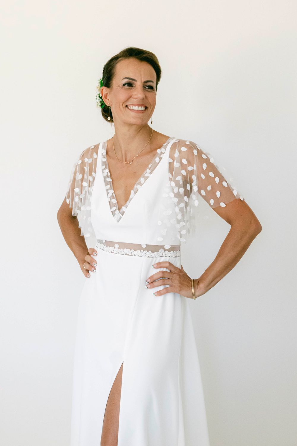 Elegant white wedding dress with sheer polka dot sleeves and v-neckline.