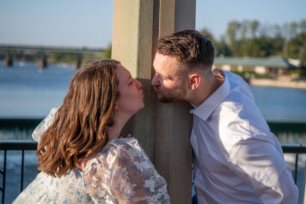 Romantic couple shares intimate moment by waterfront railing.