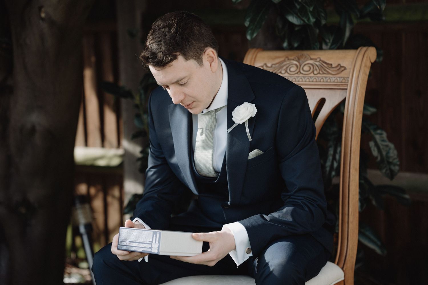 Wedding day preparation moment captured in antique wooden chair.