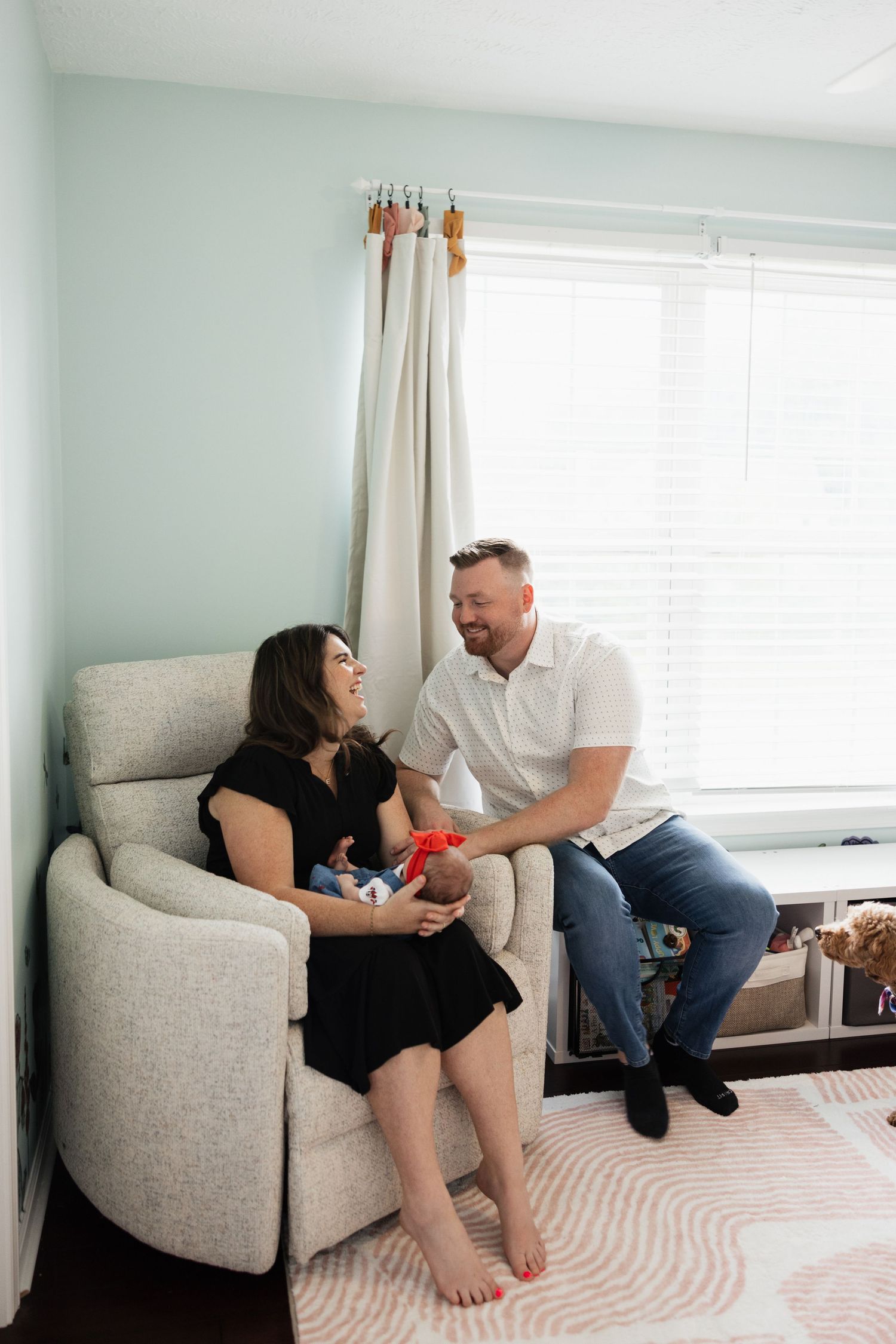 At home lifestyle newborn session in a nursery with couple and their dog.