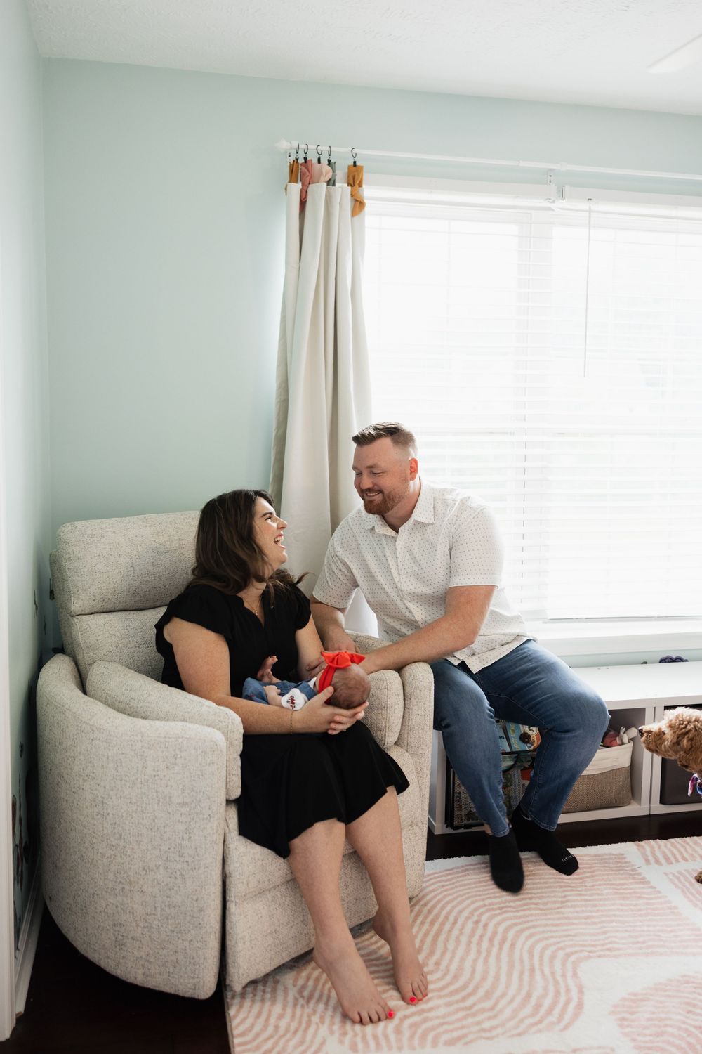 At home lifestyle newborn session in a nursery with couple and their dog.