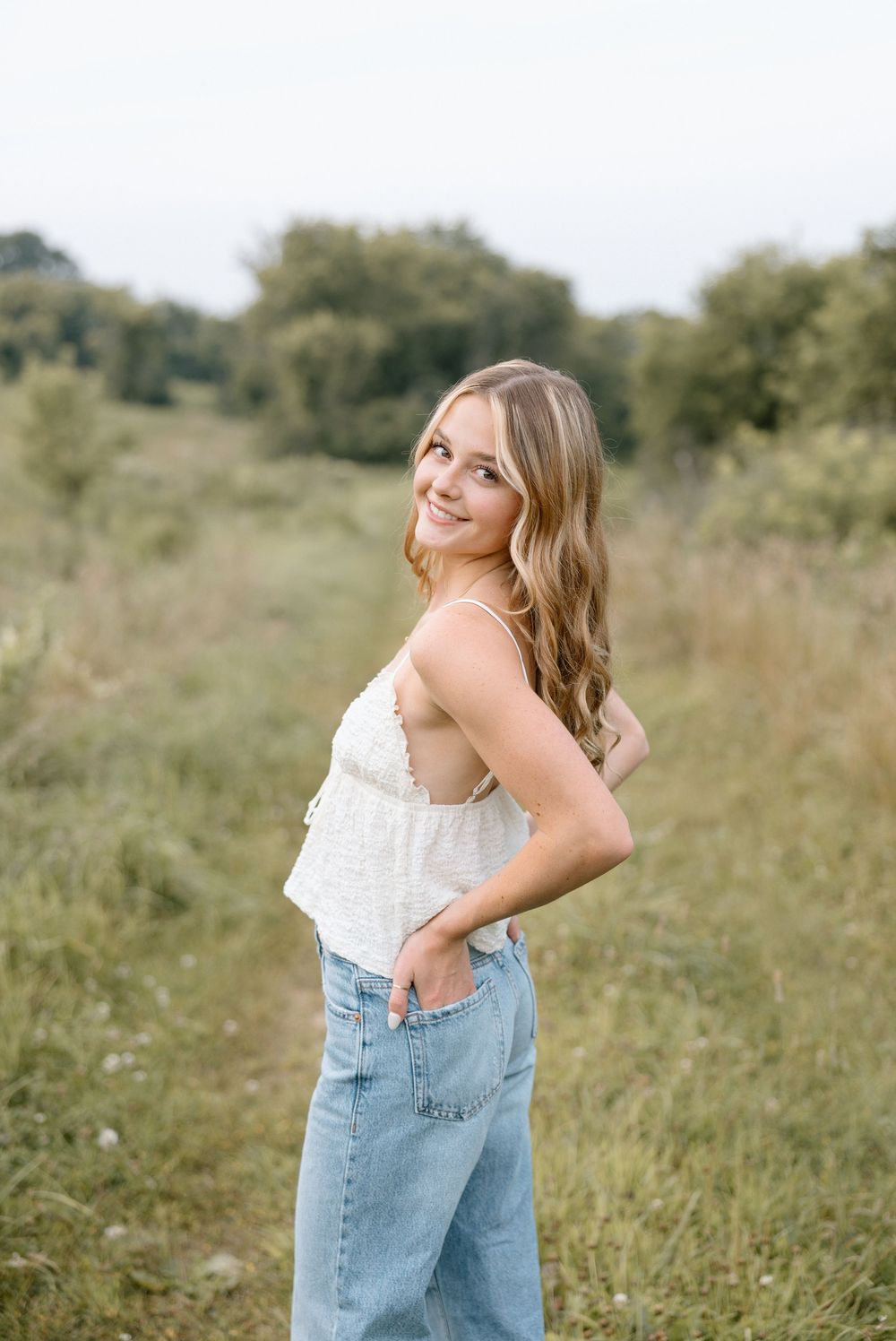 A casual summer portrait in a field wearing denim and white top.