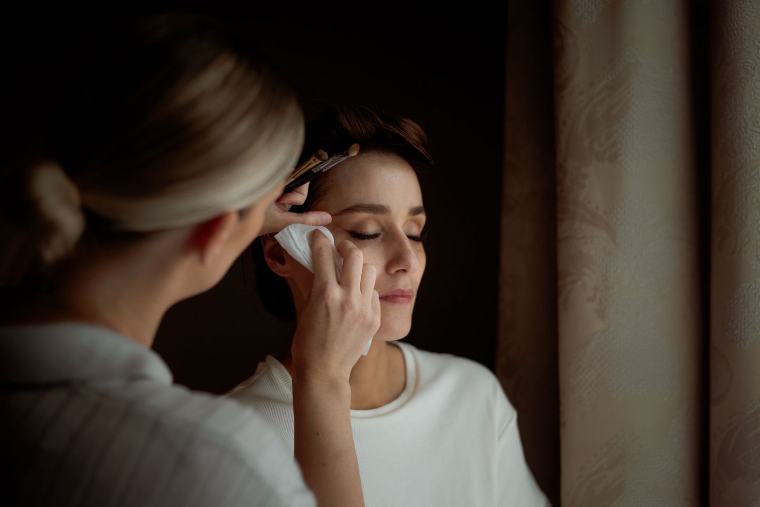 Intimate getting-ready moment showing final makeup touches being applied.
