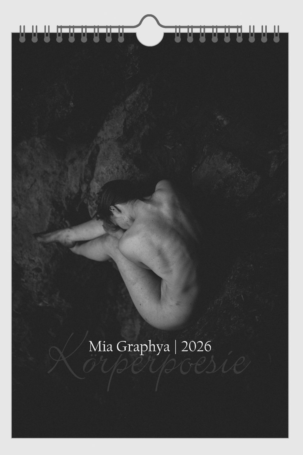 Black and white artistic nude photograph showing graceful body forms against dark background with calendar text overlay.