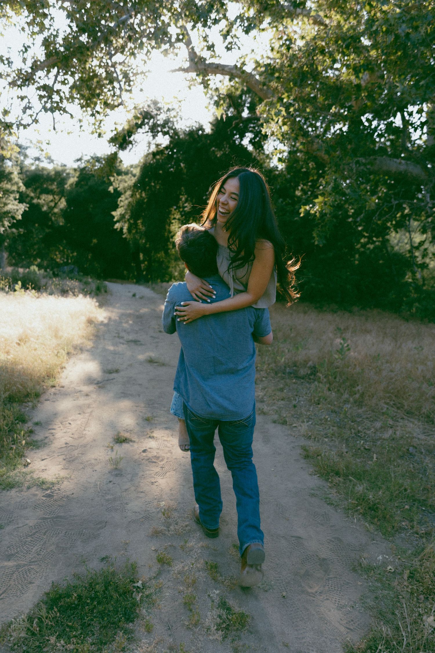A group of people dancing in a circle on a grassy hill during golden hour with trees in the background.