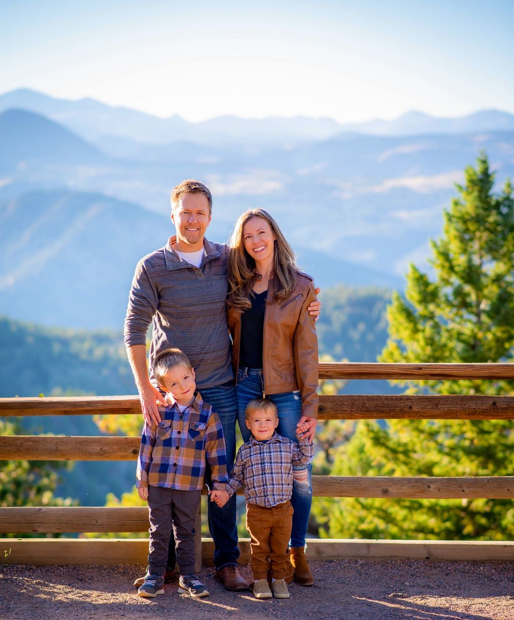 Family portrait on mountain overlook with scenic vista of blue peaks.