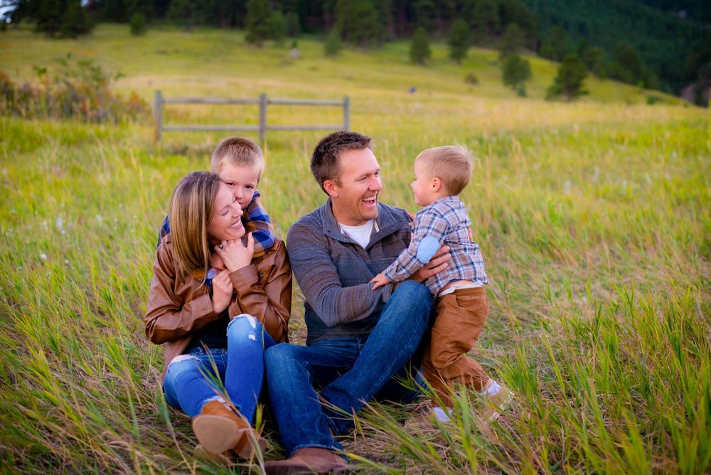 Family laying together in a grassy meadow during golden hour photography session.
