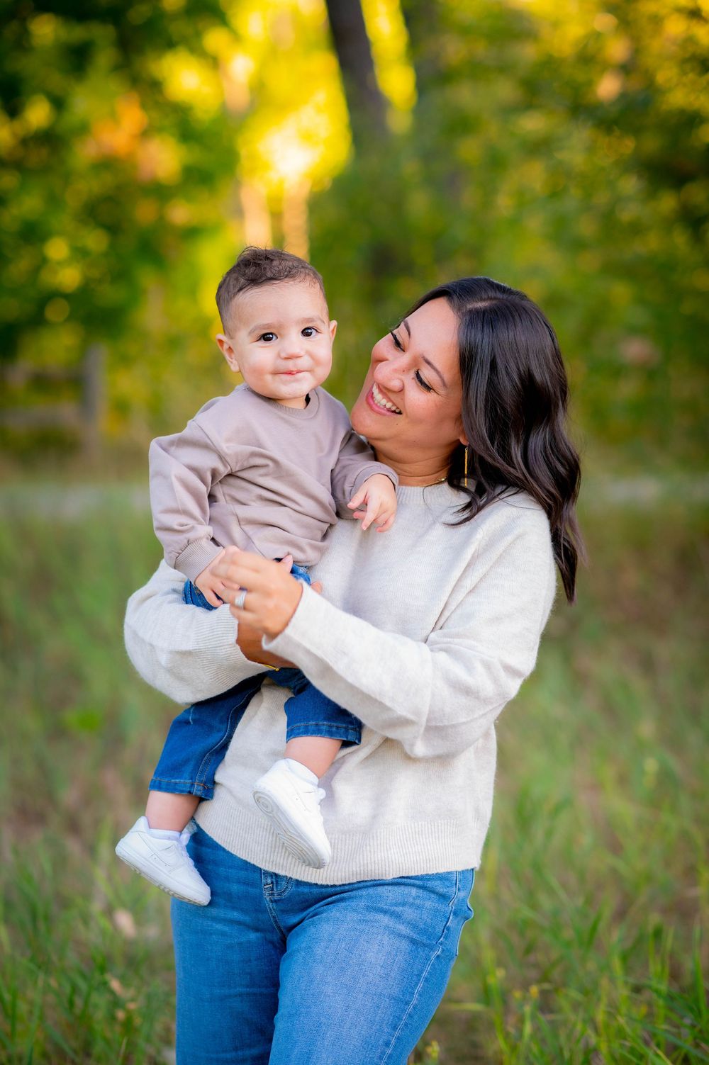 Parent and child sharing joyful moment together in sunlit outdoor setting.