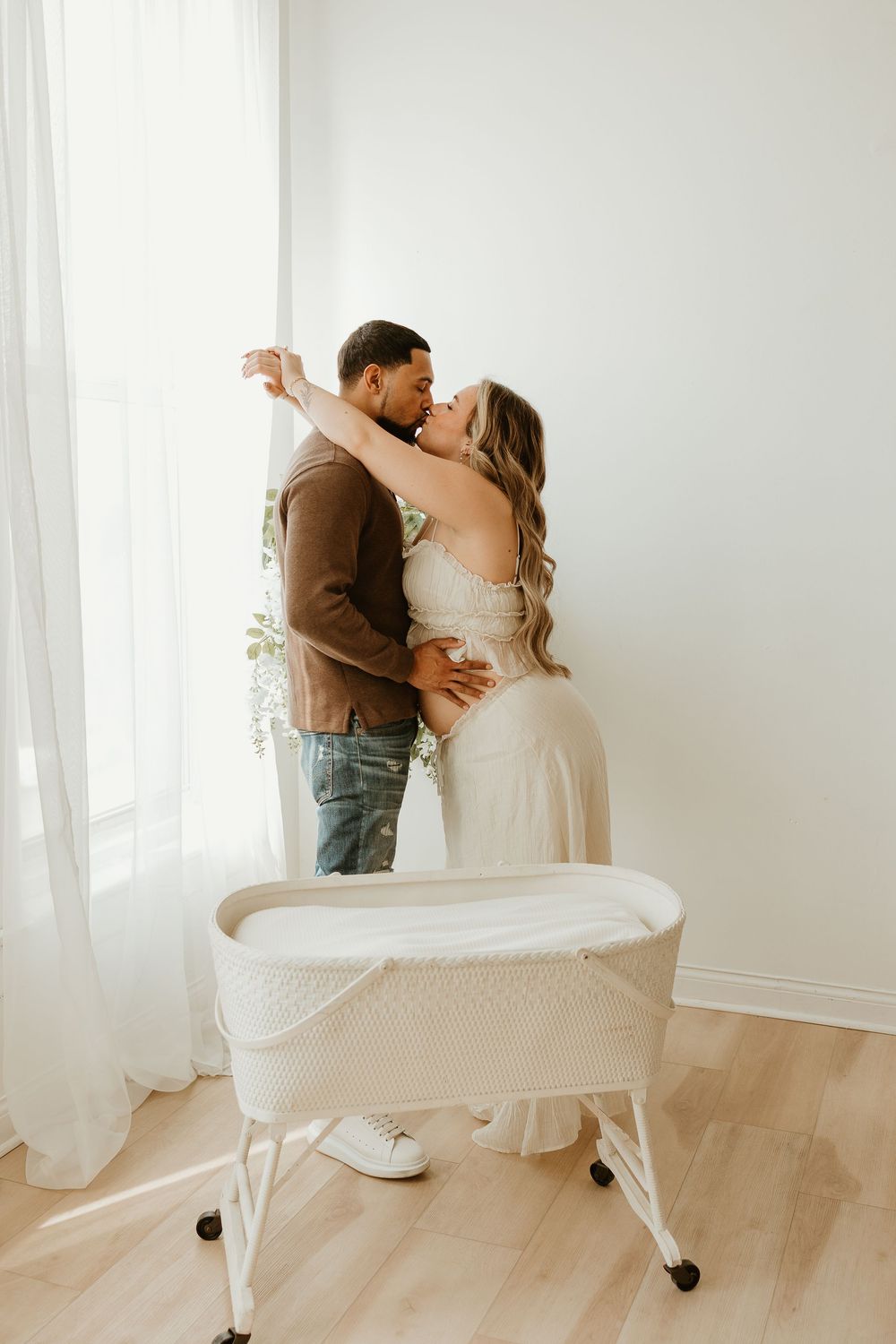 A romantic couple dances and embraces in a bright white room with flowing curtains and natural light.