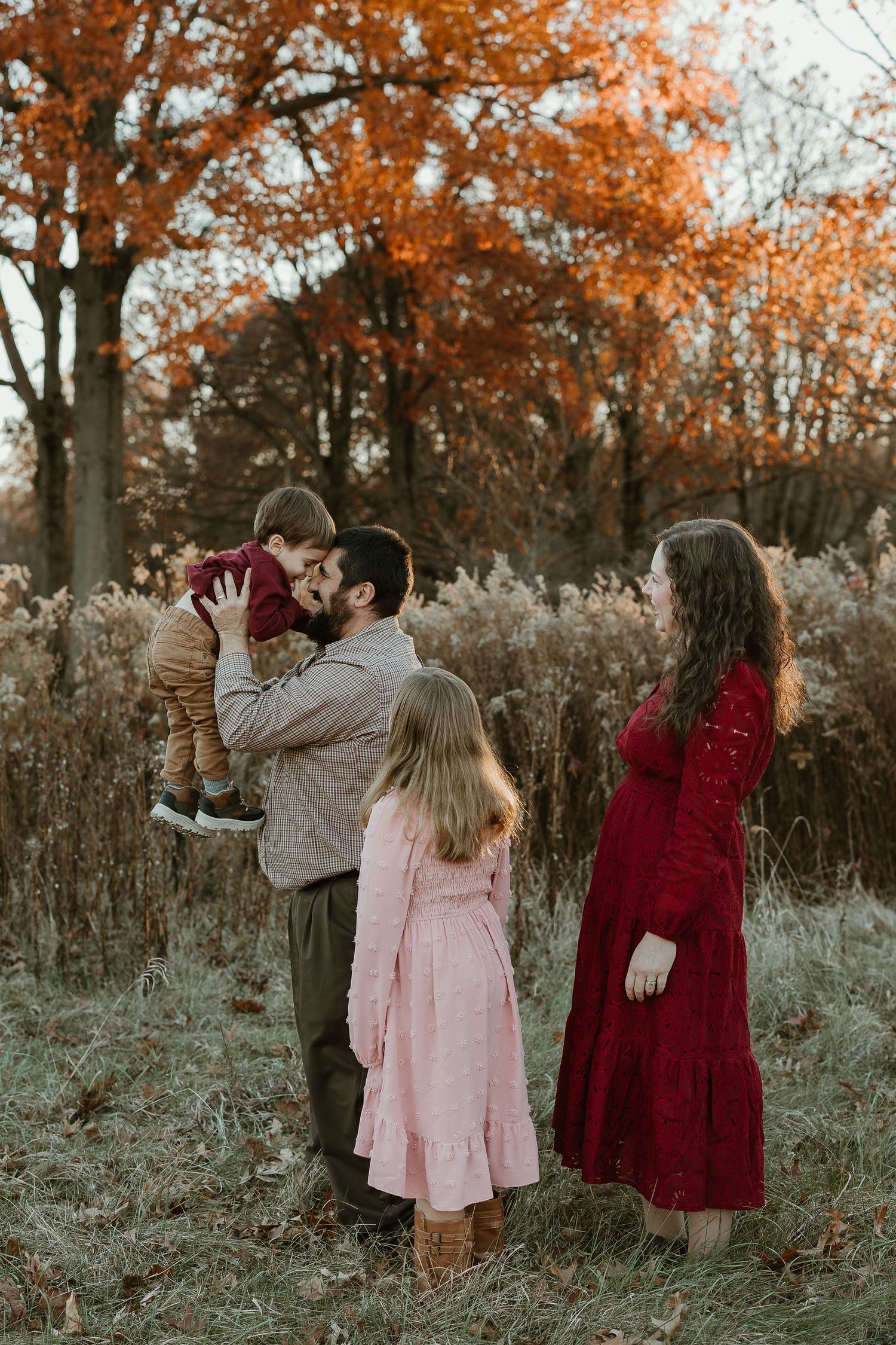 A family enjoying a tender moment together outdoors in autumn wearing coordinated earth-toned outfits.