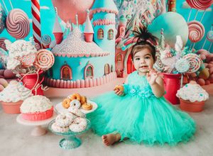 Candy-themed party decorations in turquoise and coral pink with lollipops, tulle, and dessert displays.