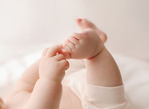 Close up of a baby's tiny fingers grasping against a soft white background in gentle lighting.