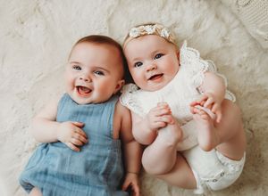 Four sequential photos showing joyful babies in white and blue outfits laying together on a light colored blanket.