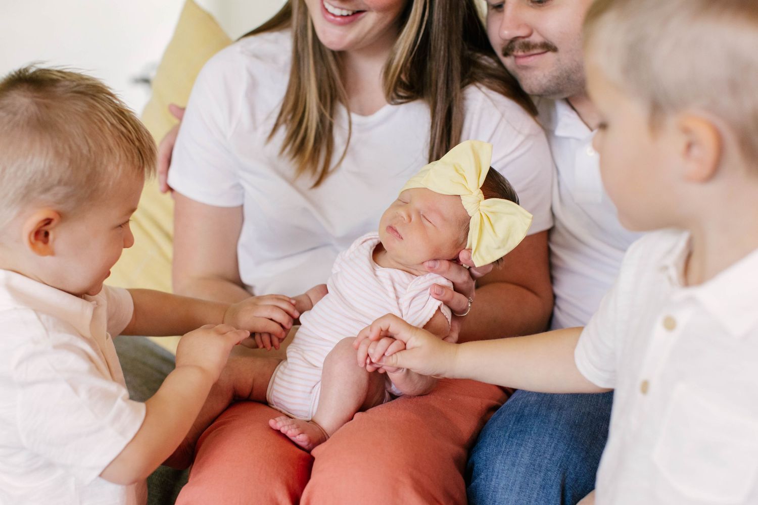Family gathered on couch spending time with newborn baby.