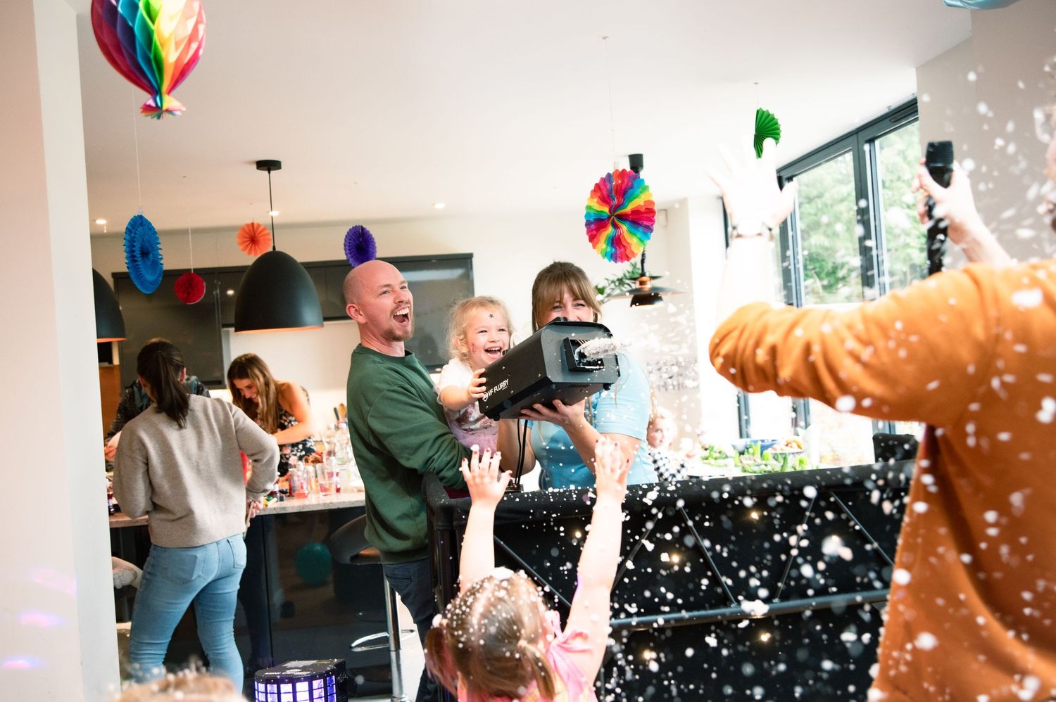 People celebrate at a lively indoor party with balloons and confetti creating a festive atmosphere.