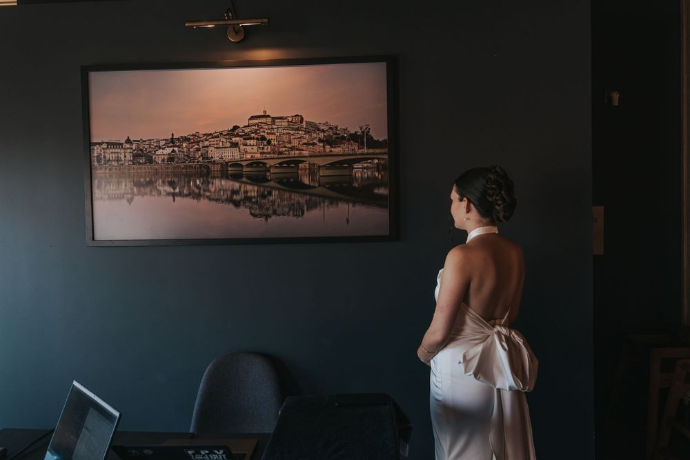 Someone in a white dress looks at a framed cityscape photo on a dark blue wall in an office setting.