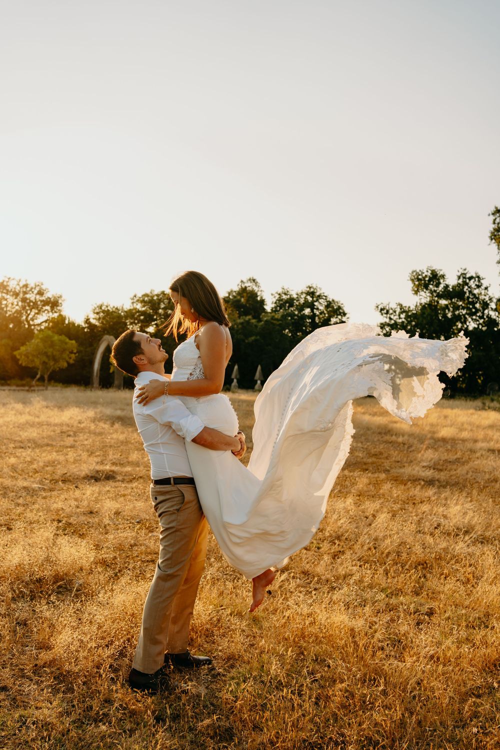 A couple in a golden field at sunset creating a playful dance dip pose during their outdoor photo session.