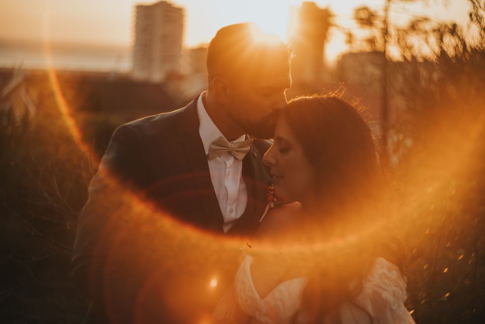 A silhouetted couple shares a romantic moment against a warm golden sunset background.