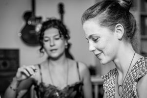 Black and white portrait photo of 2 women talking and smiling in a music studio.