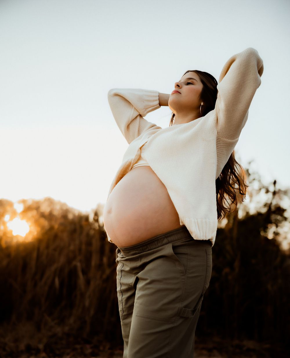Silhouetted maternity photos at sunset showing a pregnant figure in flowing dress.