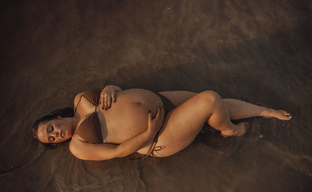 An artistic maternity boudoir photo series with dramatic lighting.