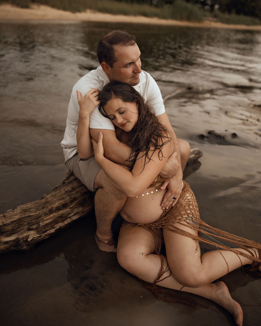 An intimate beach maternity session with a couple in white and neutral tones.