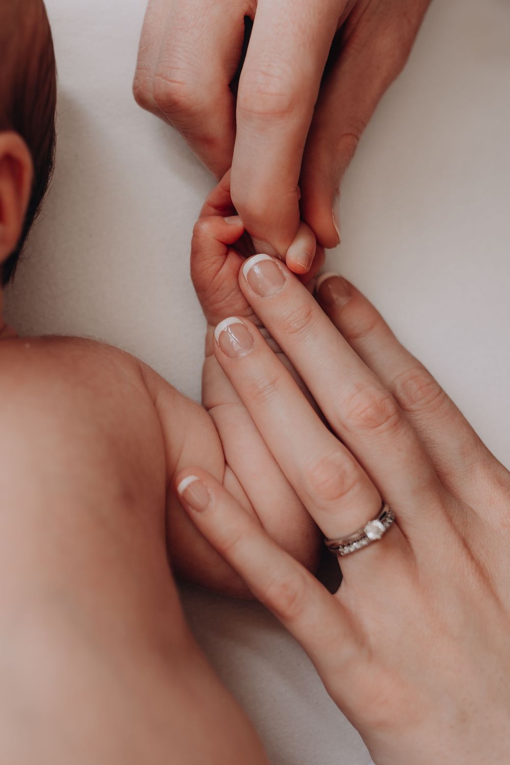 Close-up of gentle hands touching soft baby skin.