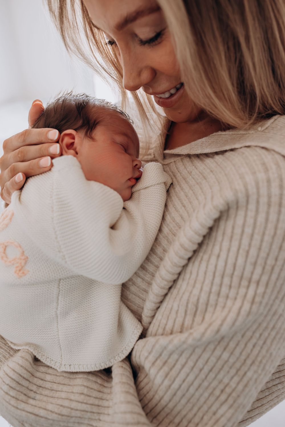 Tender moment between parent and newborn baby in cozy sweaters.