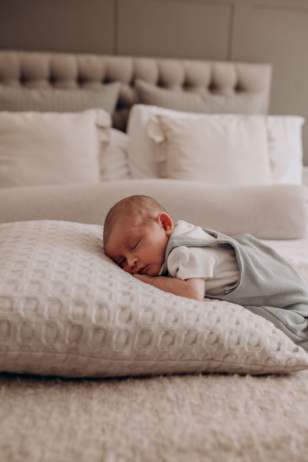 A sleeping infant rests peacefully on a textured white pillow.